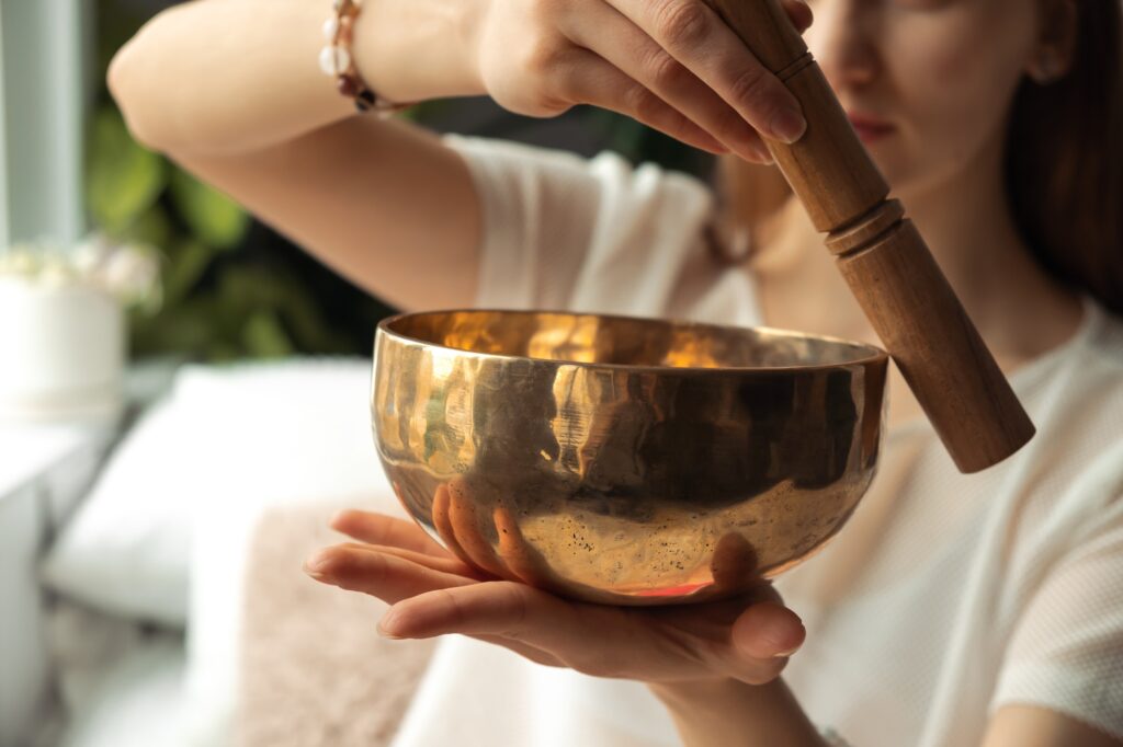 Young woman playing on a singing bowl,hands closeup.Tibetian healing sounds for yoga and meditation
